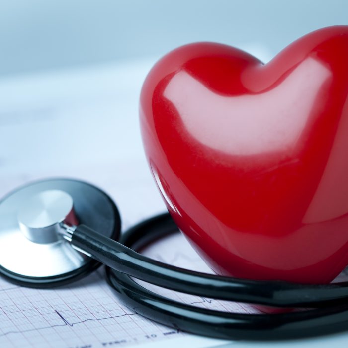Heart health concept. A heart shape on an electrocardiogram with a stethoscope. Slight blue tone. You may also like: